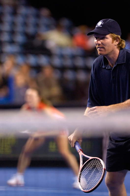 Jim Courier at net as Martina Hingis waits to return serve